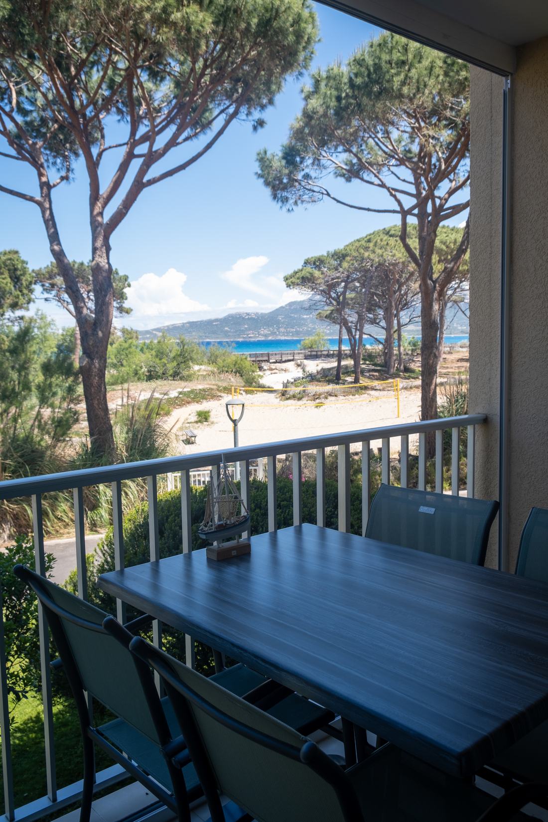 Balkontisch mit Blick durch die Pinien aufs Meer