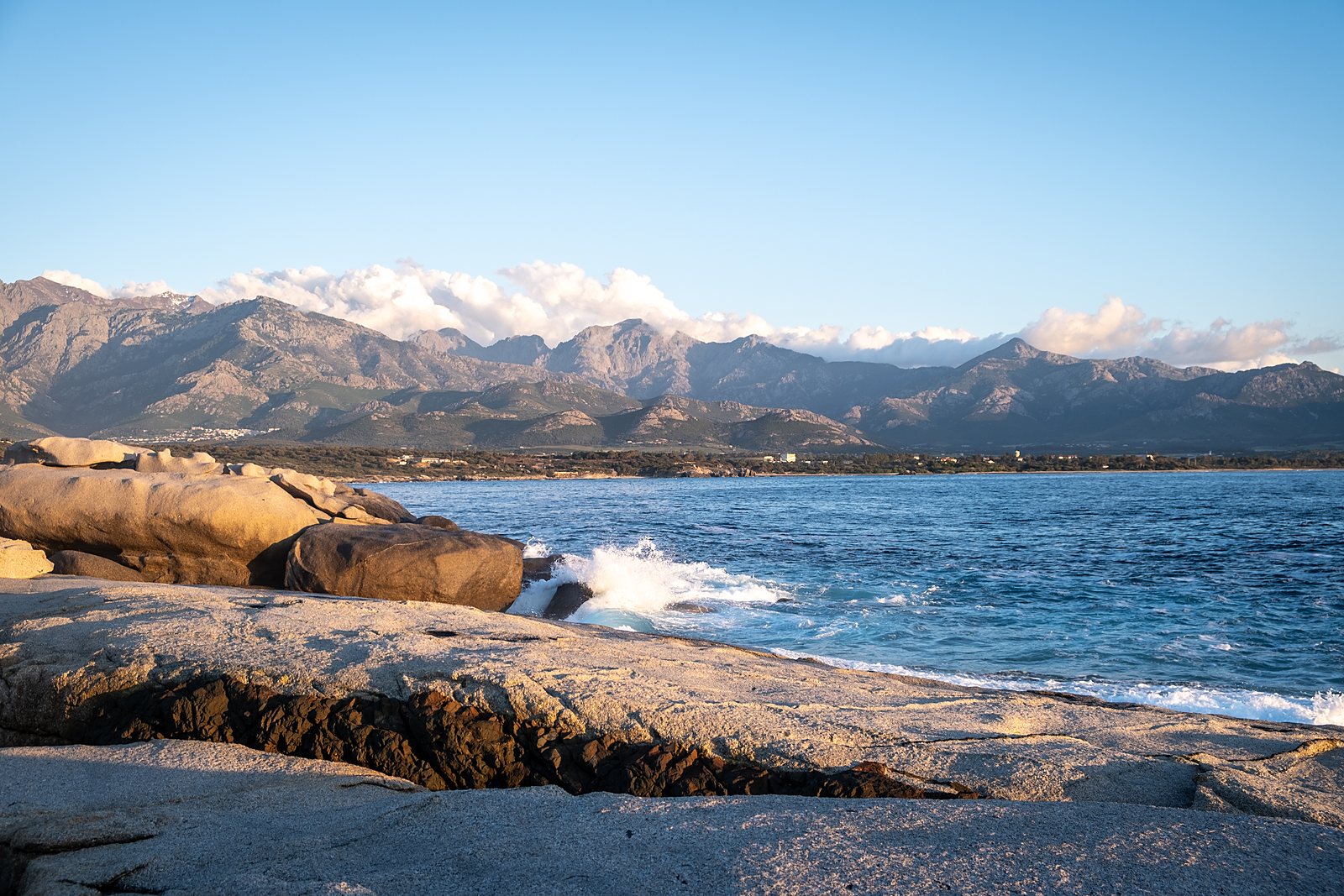 Granitfelsen am Meer, dahinter die Berge